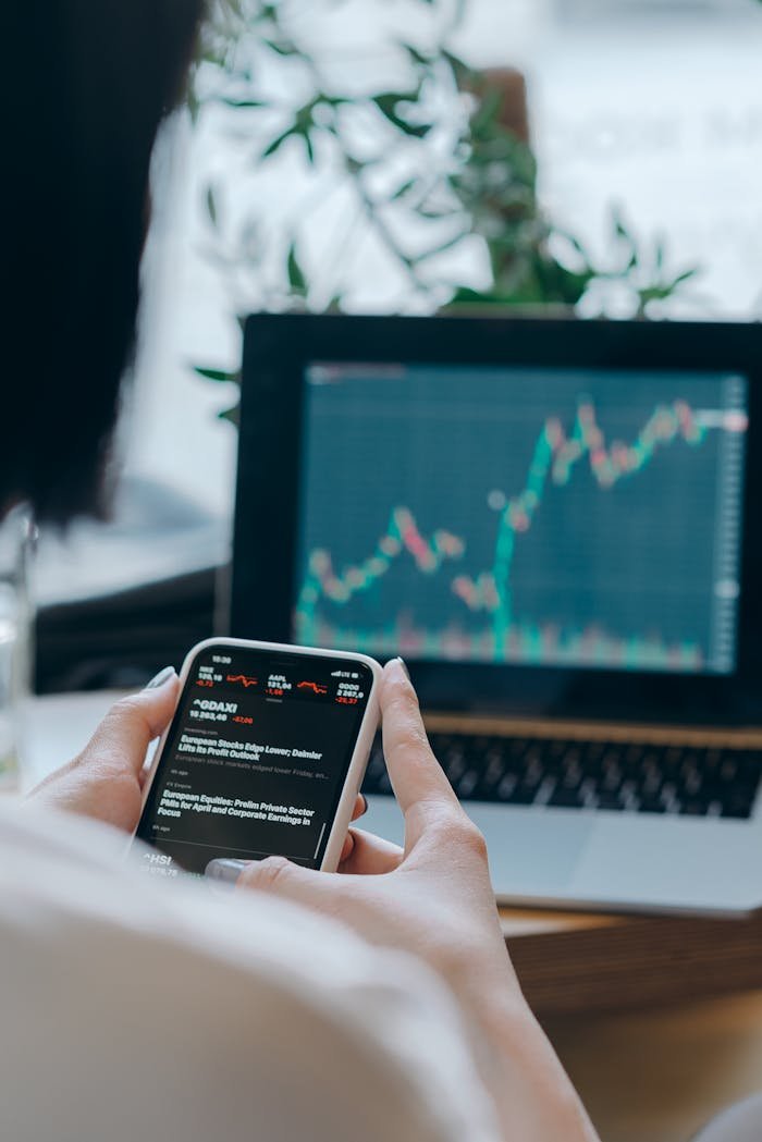about-01 Person using smartphone for stock market analysis at home office.